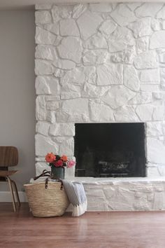 a living room with a fire place and flowers on the table in front of it