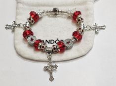 AUTHENTIC Pandora Barrel and comes with a receipt. While I use high quality beads and charms on the Pandora bracelet,  the charms and beads used on the bracelet are NOT Pandora Brand, making the bracelet very affordable.  #1  Beads and Charms include:  Red single core diamond faceted beads, crystal beads, Silver Plated Crystal Crosses, Crystal Red Heart Bead #2 beads and charms include: Crystal single core diamond faceted beads, red crystal beads, silver plated crystal crosses, crown beads Includes  Security Chain, Clasp Bead, Gift box and ships USPS Priority Mail Pandora Bracelet Shown is  7.9 barrel clasp Per Pandora  Make your jewelry the last thing you put on in the morning and first thing you take off at night. High & Dry Remove jewelry prior to swimming, bathing and other sporting/ph Red Pandora Bracelet, Pandora Red, Pandora Bracelet Designs, Night High, Crystal Cross, Red Necklace, Red Bracelets, Pandora Silver, San Clemente