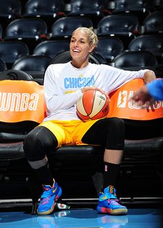 a woman sitting on a bench holding a basketball