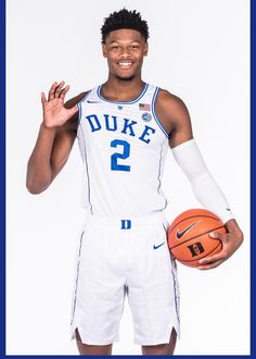 a young man holding a basketball in his right hand and posing for a photo with the ball