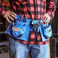 a man is holding his tool belt with tools in it