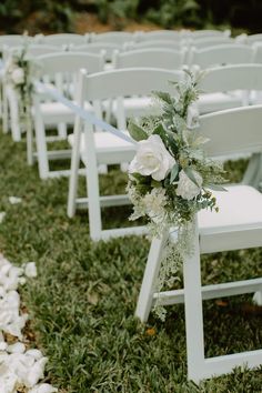 a row of white chairs sitting on top of a lush green field