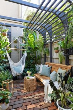 an outdoor patio with hammock, potted plants and other greenery in it