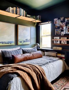 a bed sitting in a bedroom next to a window filled with pictures on the wall