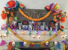 a decorated mantle with skulls and flowers in front of the fire place for dia de los muerts