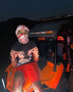 a man sitting on top of an orange vehicle