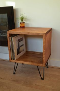 a small wooden shelf with some records on it and a potted plant next to it