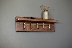 a wooden shelf with three hooks on it and a potted plant next to it