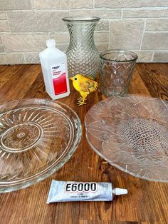 several glass dishes are sitting on a wooden table next to a bottle of cleaner and a tube of deodorant