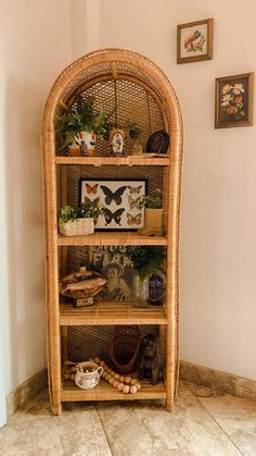 a wicker shelf with plants and pictures on it