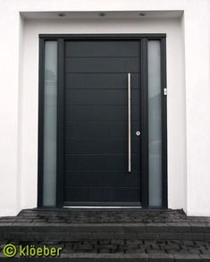 a black door is on the side of a white building