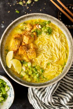 a bowl of noodle soup with tofu and green onions