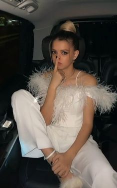 a woman sitting in the back seat of a car with her hand on her chin