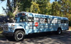 a blue school bus is parked on the side of the road in front of some trees