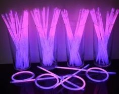 four glass vases filled with purple lite up sticks