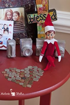 an elf sitting on top of a red table next to some silver coins and pictures