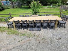 a large wooden table sitting in the middle of a gravel field next to a fence