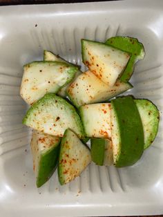 sliced cucumbers in a plastic container with seasoning on the side, ready to be eaten