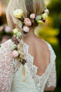 a woman with blonde hair and flowers in her hair is wearing a white lace dress