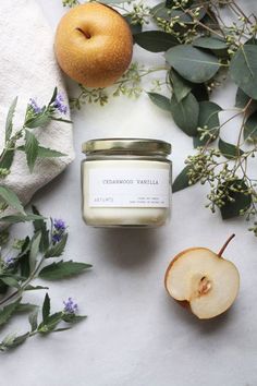 an apple sits next to a candle and some leaves on a white surface with flowers