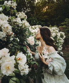 a woman in a white dress standing next to some pink and white flowers with her eyes closed