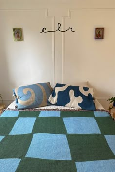 a blue and green blanket sitting on top of a bed next to two planters