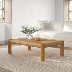 a living room with a white couch, coffee table and rugs on the floor