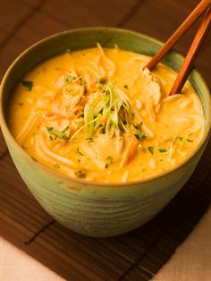 a green bowl filled with soup and chopsticks