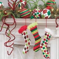 christmas stockings and stocking hanging from a mantel decorated with green, red, and white ornaments