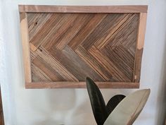 a potted plant sitting in front of a wooden wall hanging on a white wall