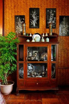 a wooden cabinet sitting next to a potted plant on top of a hard wood floor