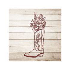 a boot with flowers in it sitting on top of a wooden floor next to a wall