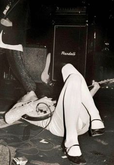 a woman laying on the ground next to a guitar and amp in black and white