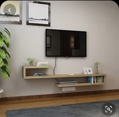 a flat screen tv sitting on top of a wooden shelf next to a potted plant