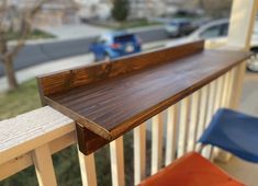 a close up of a wooden rail on a porch near a blue chair and some cars