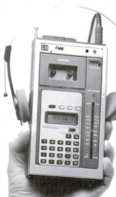 an old radio with headphones in the palm of someone's hand, holding it up