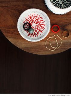 two knitted bowls on a wooden table with scissors and yarn