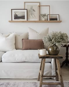 a white couch with pillows and pictures on the wall above it in a living room