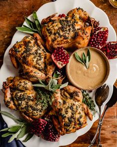 a white plate topped with meat covered in herbs and garnished with pomegranates