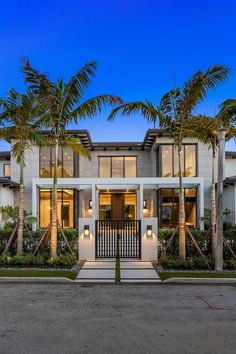 a large white house with palm trees in the front yard and entry way to it