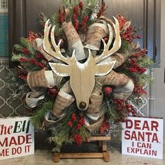 a christmas wreath with deer head and antlers on it next to two signs that say the elk made me do it