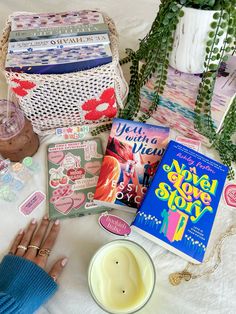 a person's hand next to some books and other items on a white blanket