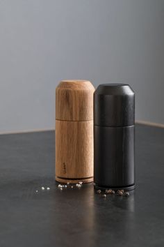 two salt and pepper shakers sitting on top of a black counter next to each other