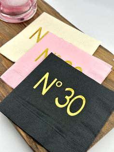 three napkins on a wooden tray with pink and yellow paper in the middle that says, q & n