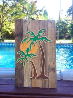 a wooden sign with a palm tree painted on it next to a pool and trees