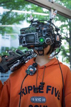 a person wearing an orange hoodie and holding a camera with wires attached to it