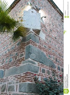 a tall brick building with a clock on it's face and palm tree in the foreground