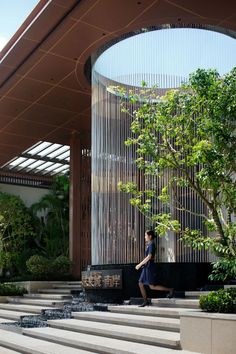 a woman is walking down some steps in front of a building with trees and bushes