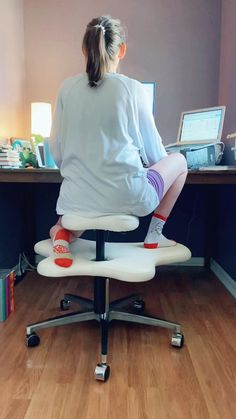 a woman sitting on top of an office chair in front of a computer