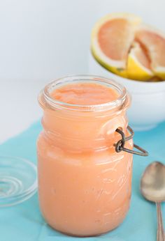 a glass jar filled with orange juice next to a bowl of sliced grapefruit